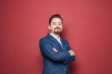 Studio portrait of proud businessman in suit on red background
