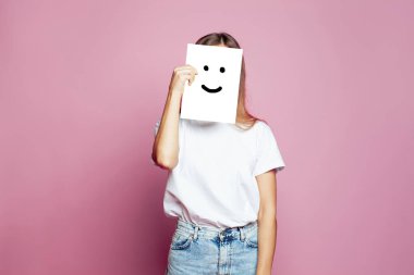 Çekici bir kadın pembe arka planda gülümseme işareti olan beyaz bir kağıt gösteriyor.