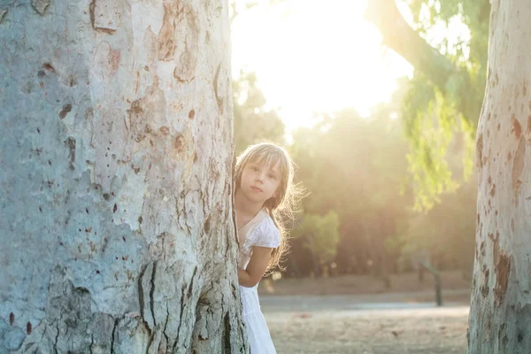 漂亮的小女孩在阳光下看着自然背景的相机 — 图库照片