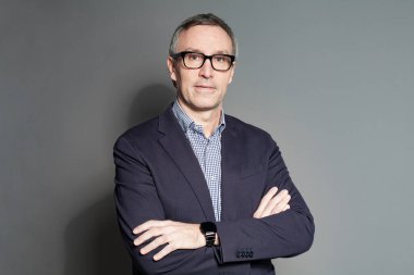 Business lifestyle. Businessman standing isolated on gray with crossed arms and smiling confident