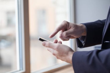 Male hands using smartphone, searching or social networks concept, hipster man typing an sms message to his friends