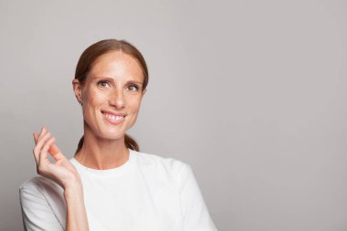 Cute middle age woman holding empty hand and smiling on white background