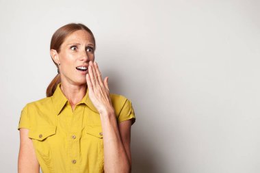 Shocked middle aged woman in casual yellow shirt on white background