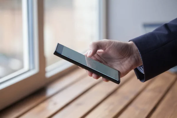 Male arm in suit holds phone closeup