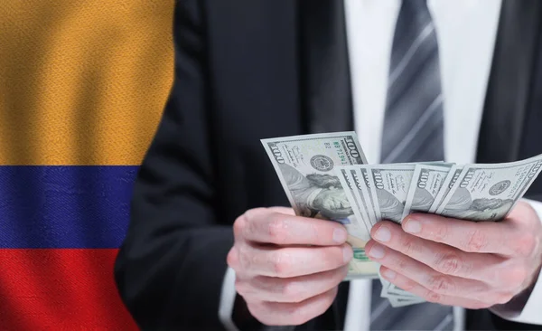 Χέρια Που Κρατούν Χρήματα Δολαρίων Στη Σημαία Της Κολομβίας — Φωτογραφία Αρχείου