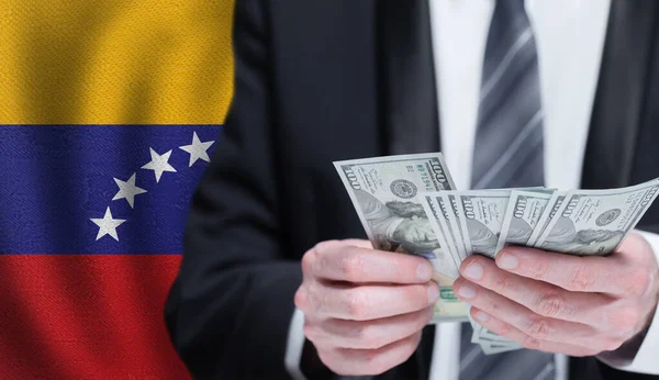 Χέρια Που Κρατούν Χρήματα Δολαρίων Στη Σημαία Της Βενεζουέλας — Φωτογραφία Αρχείου