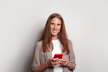 Nice cheerful mature woman using smartphone on white background