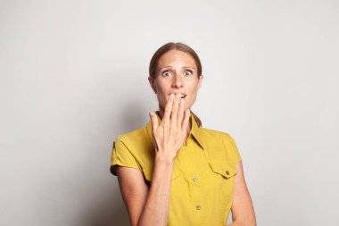 Beautiful amazed woman in yellow shirt looking at camera. Studio shot of charming surprised lady on white background.