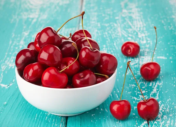 Schüssel mit frischen roten Kirschen auf blauem Holzhintergrund — Stockfoto