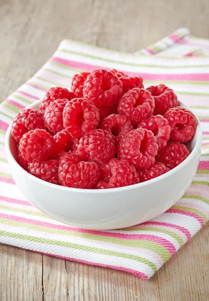 Bowl of fresh raspberries on striped tablecloth — Stock Photo, Image