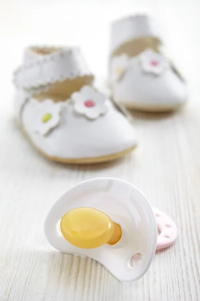 Baby pacifier and shoes — Stock Photo, Image