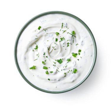 Yeşil kase ekşi krema sosu, beyaz arka planda yalıtılmış otlar, üst manzara.