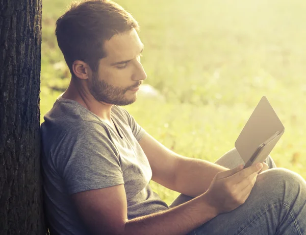 Junger Mann liest E-Book — Stockfoto