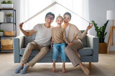 Anne, baba ve çocuk çatı sembolü olan odada. Genç aile için konut kavramı.  