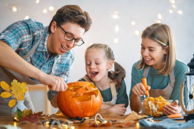 Mutlu Cadılar Bayramı! Baba ve kızları balkabağı oyuyor. Aile tatili için hazırlanıyor.