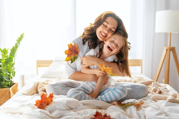 素敵な女の子と彼女の母親は晴れた朝を楽しんでいます 自宅で楽しい時間を 子供は眠りから覚める 寝室のベッドで遊ぶ家族 — ストック写真