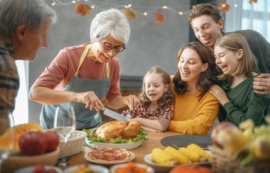 Şükran Günü, Sonbahar ziyafeti. Masada oturup bayramı kutlayan mutlu bir aile. Büyükbaba, anne, baba ve çocuklar. Geleneksel yemek..