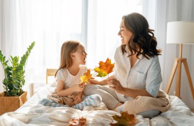 Güzel bir kız ve annesi güneşli bir sabah geçiriyorlar. Evde iyi eğlenceler. Çocuk uykudan uyanıyor. Aile yatak odasında yatakta oynuyor..