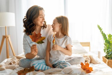 Güzel bir kız ve annesi güneşli bir sabah geçiriyorlar. Evde iyi eğlenceler. Çocuk uykudan uyanıyor. Aile yatak odasında yatakta oynuyor..