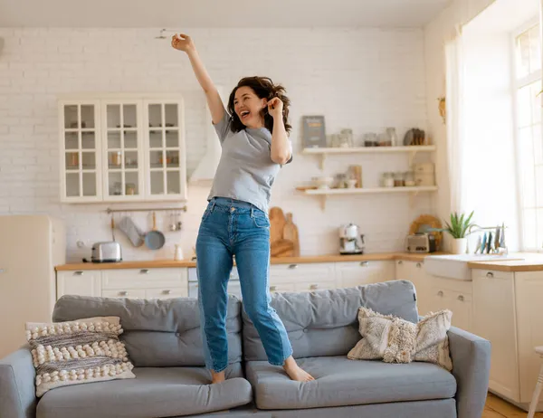 Young woman jumping on the sofa at home.