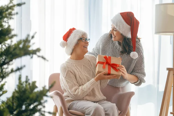 圣诞快乐 节日快乐 大妈妈和她的大女儿交换礼物 在室内的树旁玩乐 有礼物在房间里的爱的家庭 — 图库照片