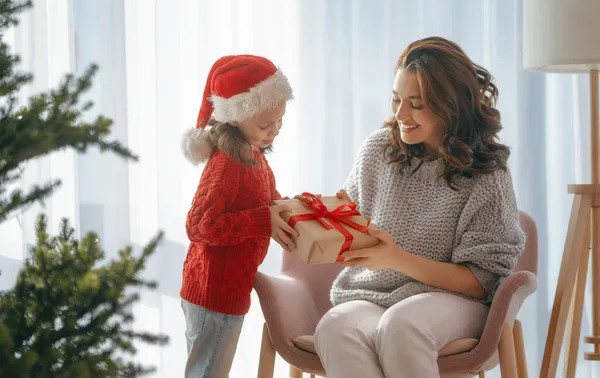 メリークリスマス ハッピーホリデー 陽気な母親とかわいい娘の女の子は贈り物を交換します 屋内で木の近くで遊んでいる親子 — ストック写真