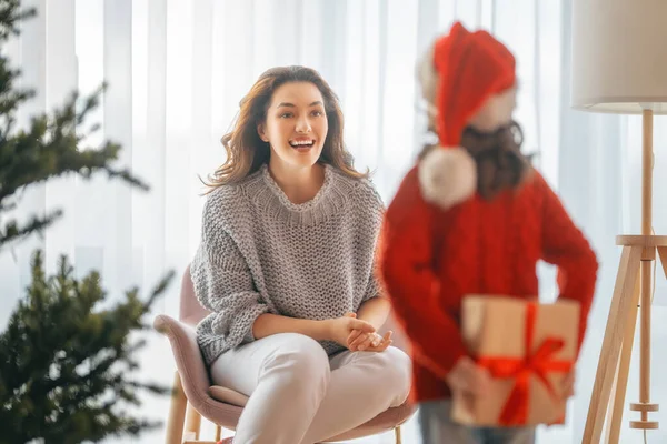 メリークリスマス ハッピーホリデー 陽気な母親とかわいい娘の女の子は贈り物を交換します 屋内で木の近くで遊んでいる親子 — ストック写真