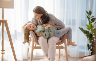 Mutlu bir gün! Anne ve kızı oynuyorlar, gülümsüyorlar ve sarılıyorlar. Aile tatili ve birliktelik. 