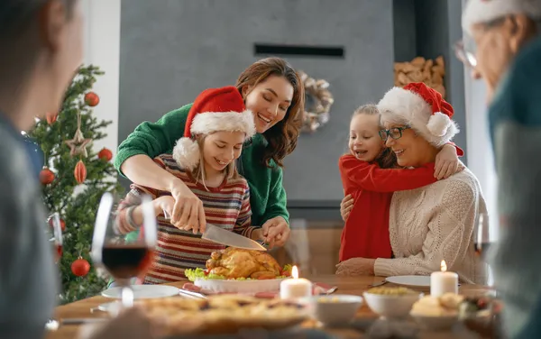 メリークリスマス幸せな家族は家で夕食を食べている ツリーの近くでお祝いの休日と団結 — ストック写真