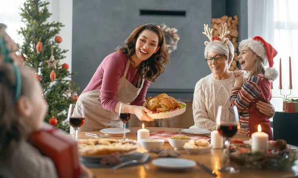 メリークリスマス幸せな家族は家で夕食を食べている ツリーの近くでお祝いの休日と団結 — ストック写真