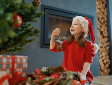 Mutlu Noeller ve mutlu tatiller. Şirin küçük kız, ağacı içeride dekore ediyor. Noel 'den önceki sabah. 