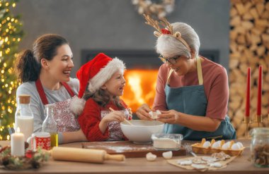 Mutlu Noeller ve mutlu tatiller. Aile hazırlığı bayram yemeği. Büyükanne, anne ve kızı kurabiye pişiriyor..