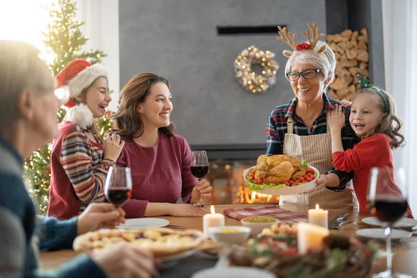 メリークリスマス幸せな家族は家で夕食を食べている ツリーの近くでお祝いの休日と団結 — ストック写真