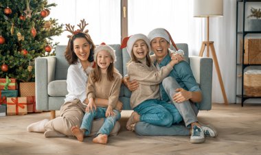 Mutlu Noeller! Güzel genç anne, baba ve kızları Noel ağacının yanında hediyelerle. 