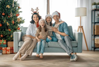 Mutlu Noeller! Güzel genç anne, baba ve kızları Noel ağacının yanında hediyelerle. 