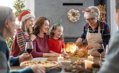 Mutlu noeller. Mutlu aile evde yemek yiyor. Kutlama tatili ve ağacın yakınındaki birliktelik.