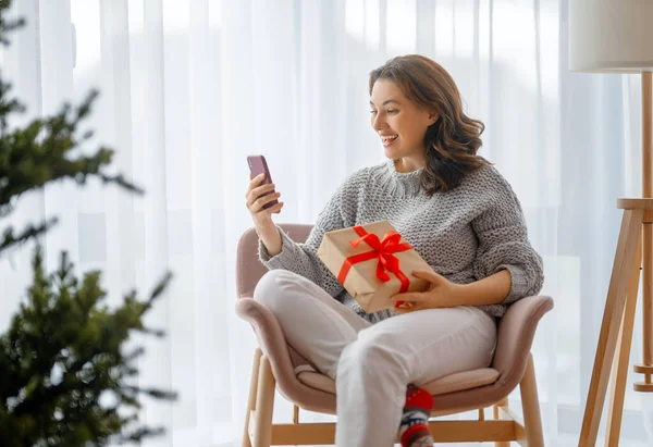 女性はクリスマスツリーの近くに座って携帯電話を使用しています — ストック写真