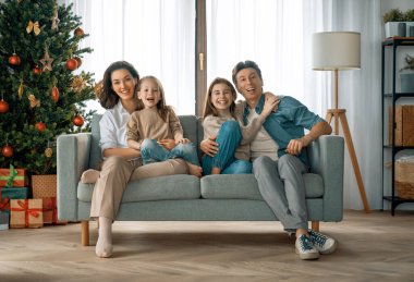 Mutlu Noeller! Güzel genç anne, baba ve kızları Noel ağacının yanında hediyelerle. 
