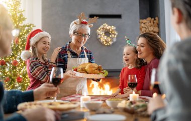 Mutlu noeller. Mutlu aile evde yemek yiyor. Kutlama tatili ve ağacın yakınındaki birliktelik.