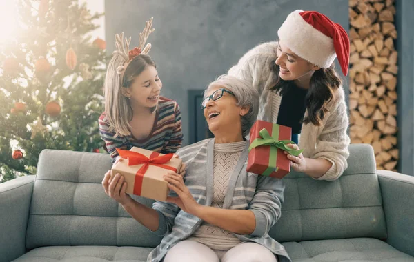 メリークリスマスとハッピーホリデー ママとおばあちゃんへの贈り物を提示する陽気な子供 屋内で木の近くで遊んでいる親と小さな子供 プレゼント付きの家族を愛する — ストック写真