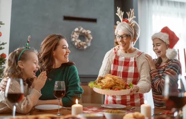 メリークリスマス幸せな家族は家で夕食を食べている ツリーの近くでお祝いの休日と団結 — ストック写真