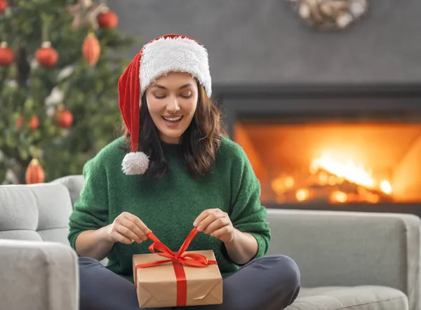 ハッピー ホリデー 陽気かなり若い女性がプレゼントを持っていた クリスマスツリーの近くで遊んでいる女の子屋内 — ストック写真