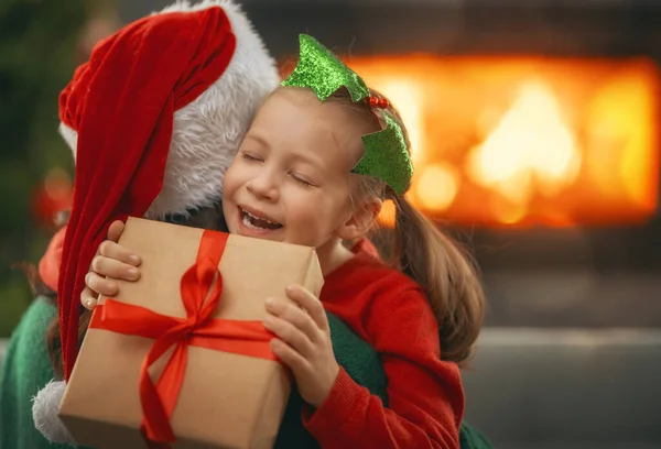 メリークリスマスとハッピーホリデー 陽気な母親とかわいい娘の女の子は贈り物を交換します 屋内で木の近くで遊んでいるお母さんと小さな子供 プレゼント付きの家族を愛する — ストック写真