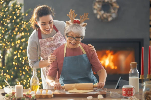 Merry Christmas and Happy Holidays. Family preparation holiday food. Mother and daughter cooking gingerbread cookies.