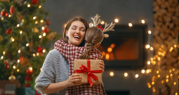 メリークリスマスとハッピーホリデー 陽気な母親とかわいい娘の女の子は贈り物を交換します 屋内で木の近くで遊んでいるお母さんと小さな子供 プレゼント付きの家族を愛する — ストック写真