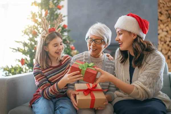 メリークリスマスとハッピーホリデー ママとおばあちゃんへの贈り物を提示する陽気な子供 屋内で木の近くで遊んでいる親と小さな子供 プレゼント付きの家族を愛する — ストック写真