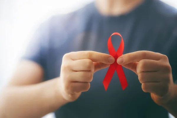 World Aids Day. Red ribbon in the hands close up