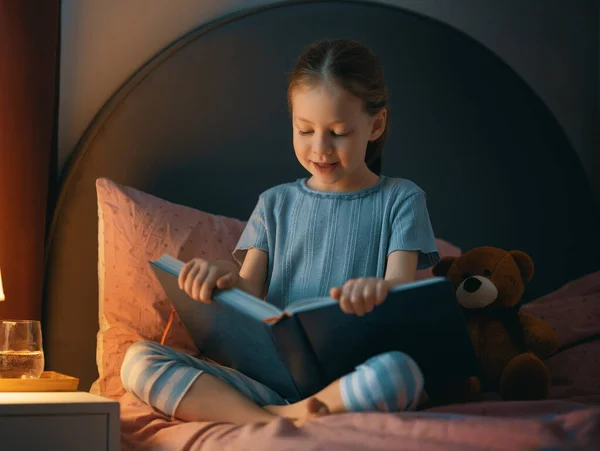 Χαριτωμένο Κοριτσάκι Διαβάζει Ένα Βιβλίο Στην Κρεβατοκάμαρά Της — Φωτογραφία Αρχείου