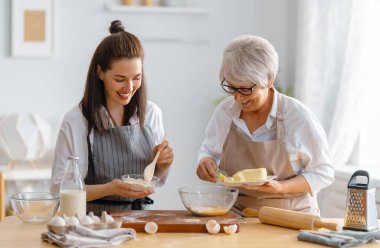Mutfakta mutlu bir aile. Anne ve yetişkin kızı pasta hazırlıyorlar..
