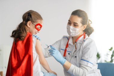 Hastanede çocuk aşılayan doktor. Süper kahraman kostümlü çocuk..